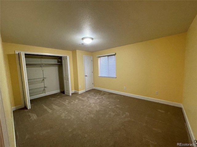 unfurnished bedroom with dark colored carpet, a closet, visible vents, and baseboards