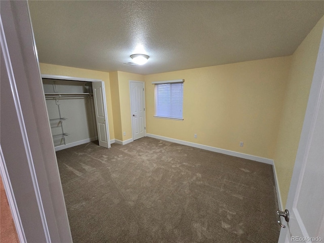 unfurnished bedroom with a textured ceiling, carpet floors, a closet, and baseboards