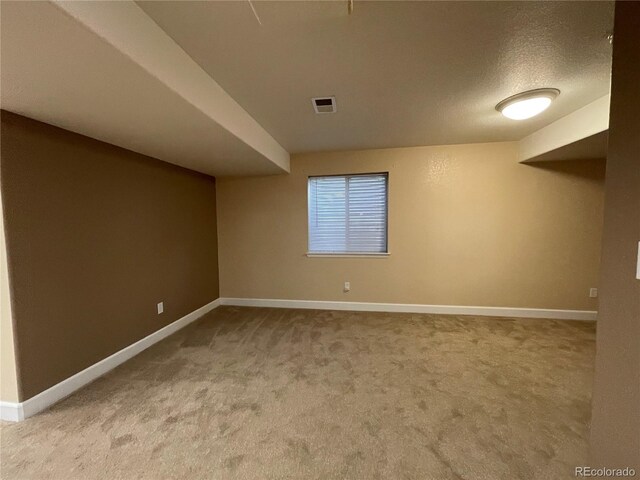 unfurnished room featuring carpet floors, baseboards, visible vents, and a textured ceiling