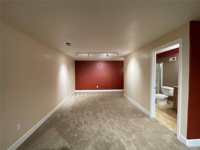 unfurnished room featuring carpet floors, rail lighting, baseboards, and visible vents