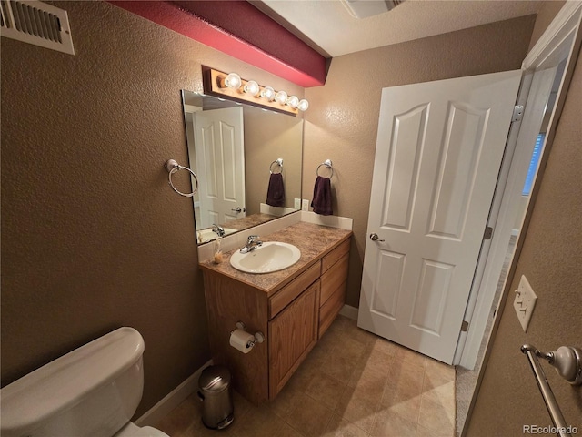 half bath with baseboards, visible vents, vanity, and toilet