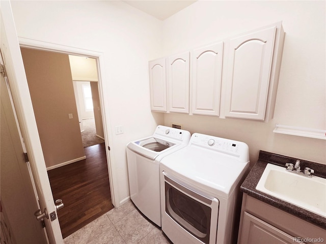 clothes washing area featuring cabinet space, light tile patterned floors, a sink, and washing machine and clothes dryer