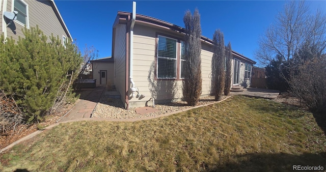 view of side of home featuring entry steps and a yard