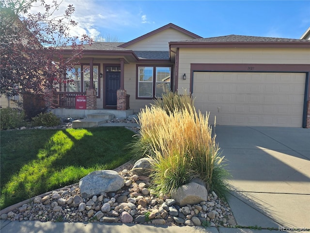 view of front facade with driveway, covered porch, an attached garage, and a front yard