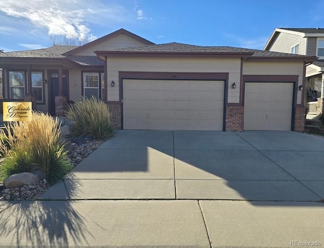 single story home with concrete driveway, an attached garage, and brick siding