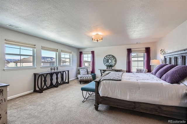 bedroom featuring multiple windows, light carpet, and a textured ceiling