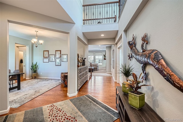 foyer entrance featuring wood-type flooring, an inviting chandelier, and a high ceiling