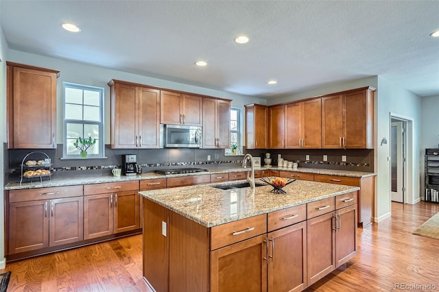 kitchen featuring a center island with sink, sink, appliances with stainless steel finishes, and light hardwood / wood-style flooring