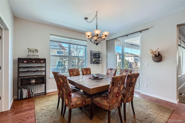 dining area featuring dark wood-type flooring and a notable chandelier