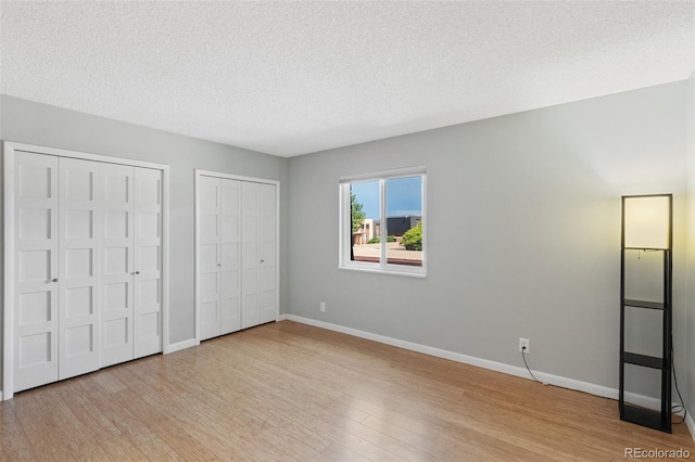 2973 Mesa Rd Unit C, Colorado Springs, CO 80904 - unfurnished bedroom featuring multiple closets, wood finished floors, and a textured ceiling