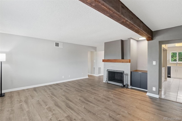 2973 Mesa Rd Unit C, Colorado Springs, CO 80904 - unfurnished living room featuring light wood finished floors, a textured ceiling, a fireplace, and beam ceiling
