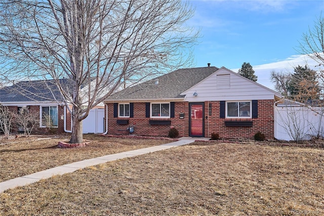 view of front of property featuring brick siding, fence, and a front lawn