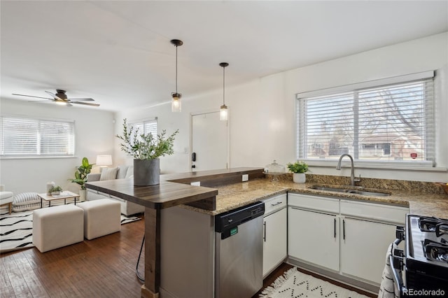 kitchen with open floor plan, a peninsula, stainless steel dishwasher, white cabinetry, and a sink