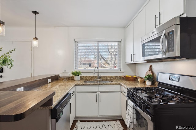 kitchen with wood counters, white cabinetry, stainless steel appliances, and a sink