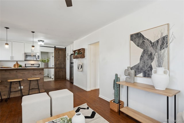 living area featuring dark wood-style floors, a barn door, and baseboards