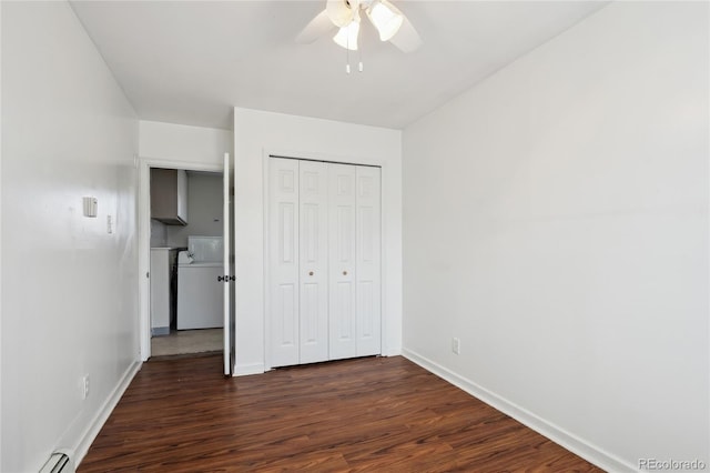 unfurnished bedroom with baseboards, washer / clothes dryer, dark wood-style flooring, baseboard heating, and a closet