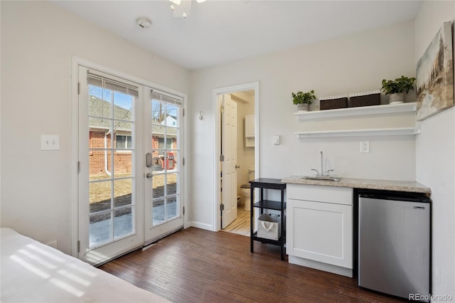 bar featuring dark wood finished floors, freestanding refrigerator, a sink, french doors, and indoor wet bar