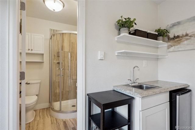 bar featuring light wood-type flooring, a sink, and baseboards