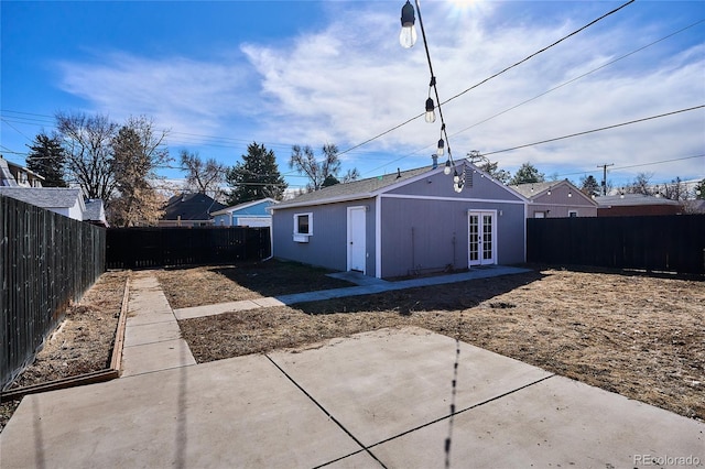 view of outdoor structure with a fenced backyard, an outbuilding, and french doors