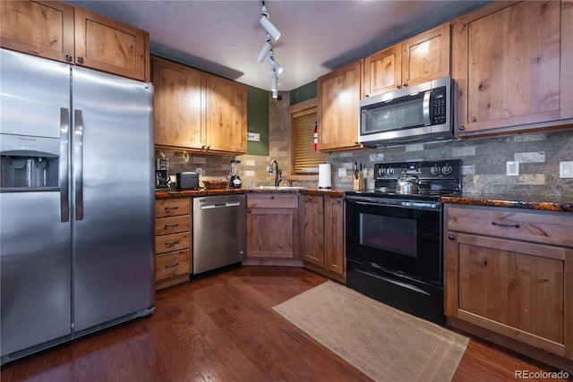 kitchen with dark hardwood / wood-style flooring, tasteful backsplash, dark stone counters, stainless steel appliances, and sink