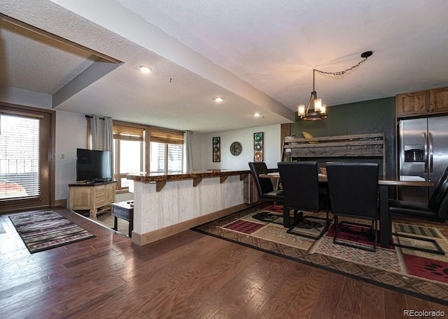 dining space with hardwood / wood-style flooring, a textured ceiling, and an inviting chandelier