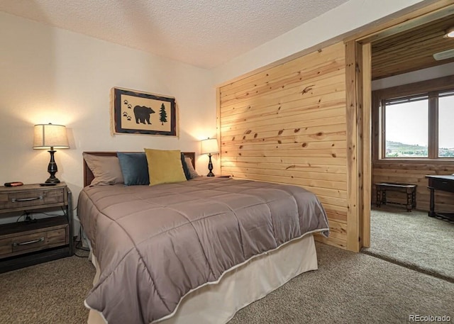 bedroom with carpet, a textured ceiling, and wood walls