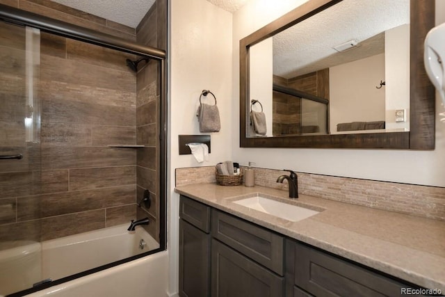 bathroom featuring tasteful backsplash, vanity, enclosed tub / shower combo, and a textured ceiling