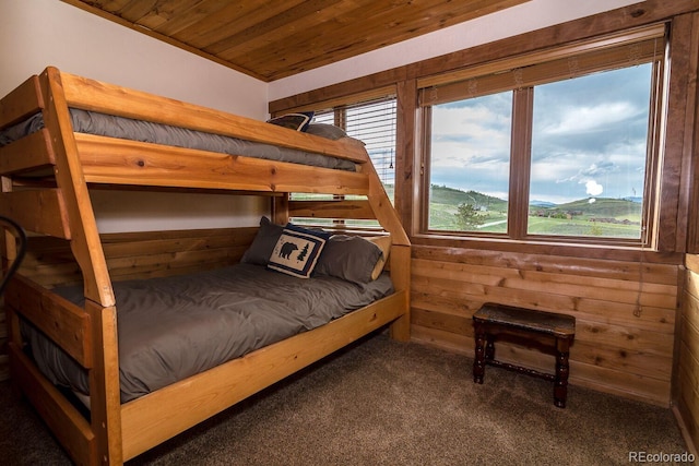 bedroom featuring a mountain view, dark colored carpet, wooden ceiling, and wood walls