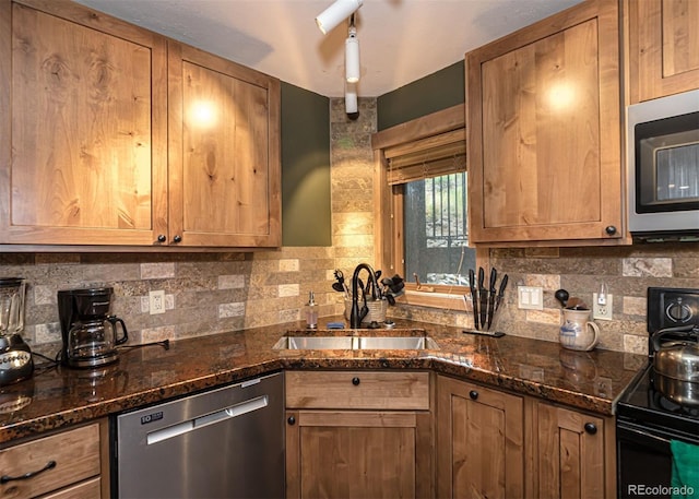 kitchen with decorative backsplash, appliances with stainless steel finishes, dark stone countertops, and sink