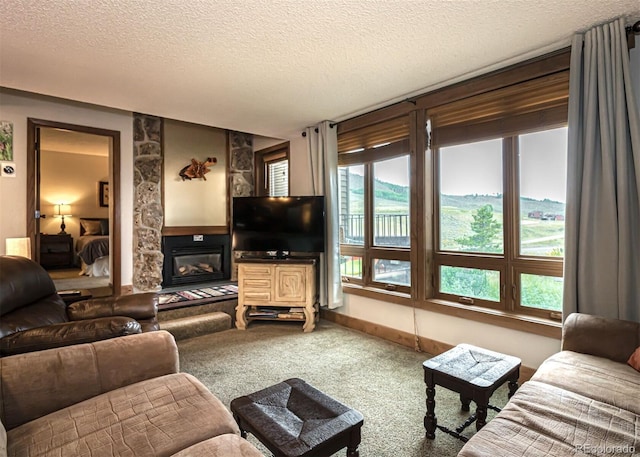 carpeted living room featuring a stone fireplace and a textured ceiling