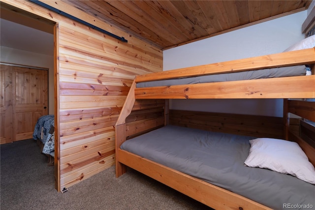 carpeted bedroom with wooden walls and wood ceiling