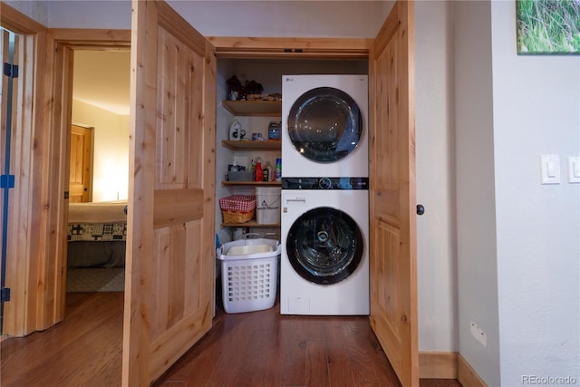 laundry room with stacked washer / drying machine and dark hardwood / wood-style flooring