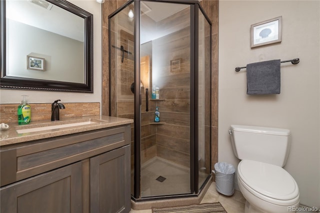 bathroom featuring tile patterned floors, vanity, toilet, and a shower with shower door