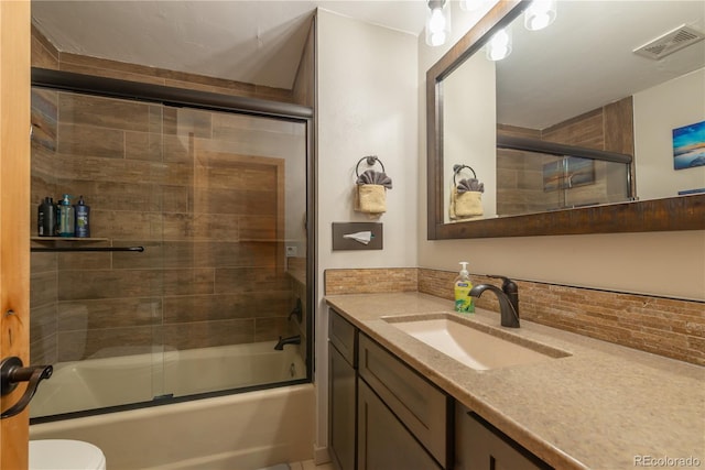 full bathroom featuring shower / bath combination with glass door, decorative backsplash, vanity, and toilet