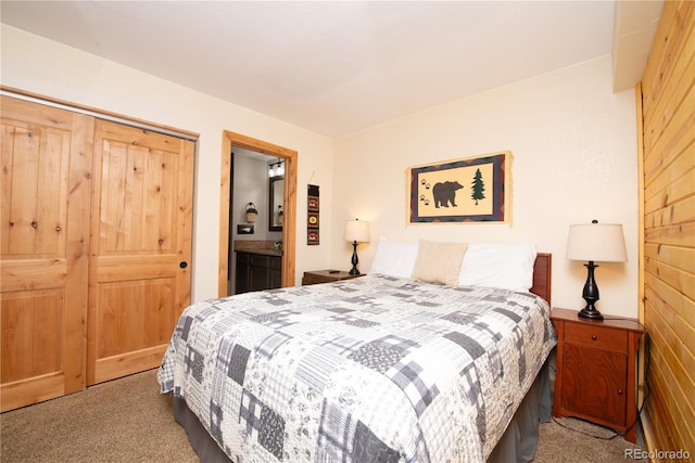 carpeted bedroom with wood walls, a closet, and ensuite bath