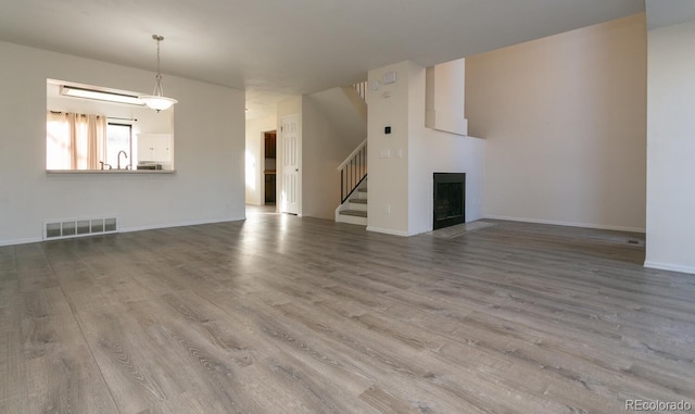 7900 W Layton Ave Unit 833, Littleton, CO 80123 - unfurnished living room with stairway, wood finished floors, a sink, a fireplace with flush hearth, and baseboards
