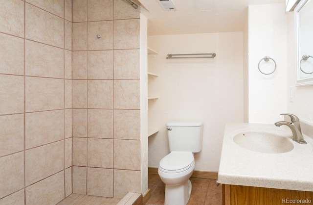 bathroom with tiled shower, tile patterned floors, vanity, and toilet