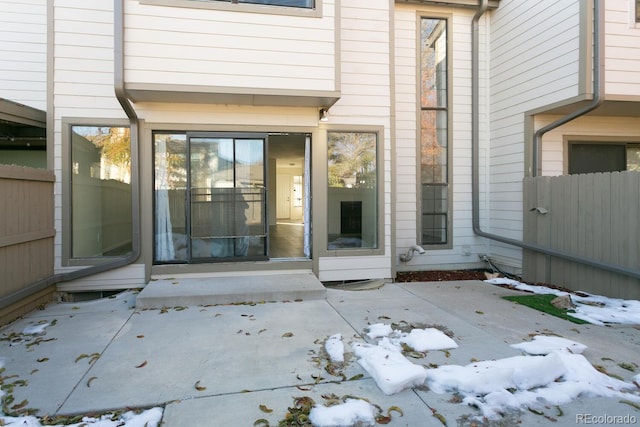 snow covered property entrance featuring a patio area