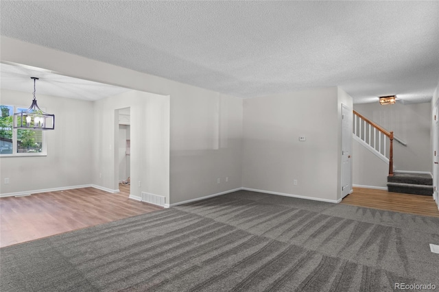 6240 W 110th Pl, Westminster, CO 80020 - unfurnished living room featuring carpet flooring, stairway, a textured ceiling, a chandelier, and wood finished floors