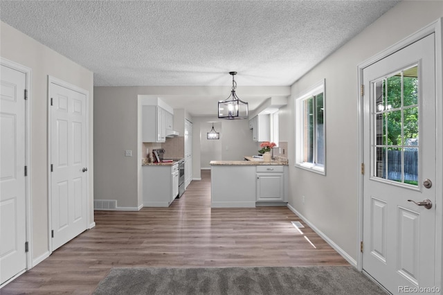 6240 W 110th Pl, Westminster, CO 80020 - kitchen with electric range, white cabinetry, light wood-style flooring, a chandelier, and a textured ceiling