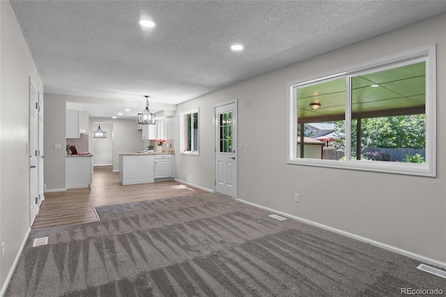 6240 W 110th Pl, Westminster, CO 80020 - unfurnished living room with a textured ceiling, a chandelier, light carpet, and recessed lighting