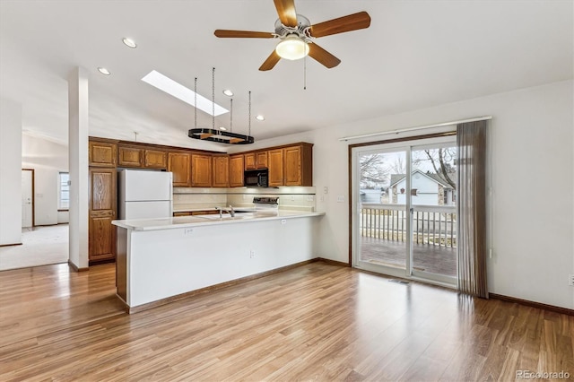 kitchen with range, a skylight, light hardwood / wood-style flooring, kitchen peninsula, and white fridge