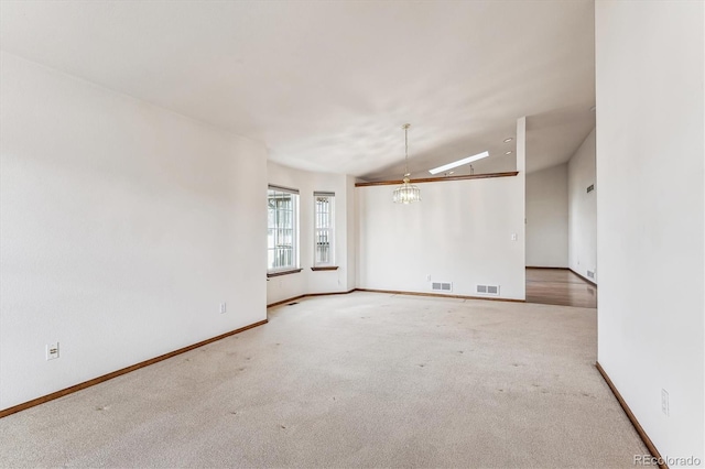 carpeted empty room with vaulted ceiling and a notable chandelier