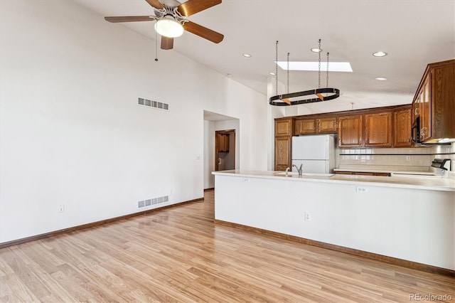 kitchen featuring light hardwood / wood-style flooring, stove, white refrigerator, tasteful backsplash, and kitchen peninsula