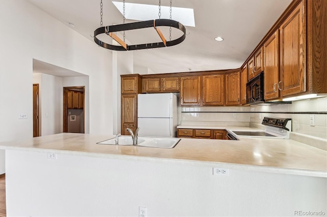 kitchen with sink, range, vaulted ceiling, kitchen peninsula, and white fridge