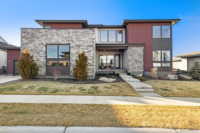 contemporary house featuring stone siding and a front lawn