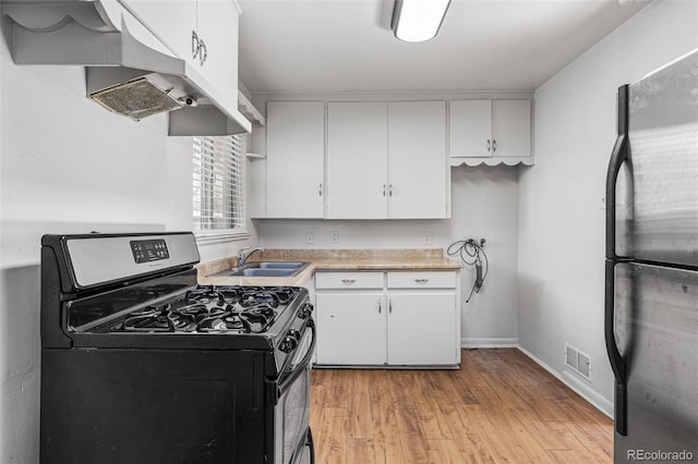 kitchen with white cabinets, sink, stainless steel fridge, light hardwood / wood-style floors, and gas stove