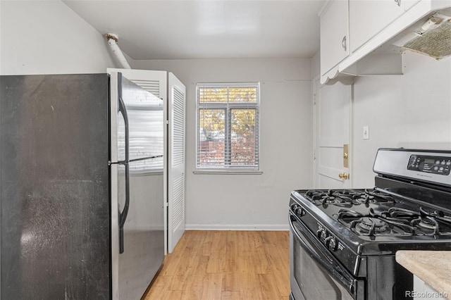 kitchen with white cabinetry, black gas range oven, stainless steel refrigerator, and light hardwood / wood-style flooring