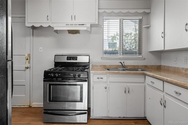 kitchen with gas stove, sink, hardwood / wood-style flooring, white cabinetry, and range hood