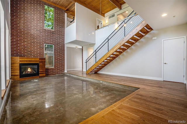 4258 Tennyson St Unit 101, Denver, CO 80212 - unfurnished living room with a high ceiling, stairway, a glass covered fireplace, a wooden ceiling with exposed beams, and brick wall